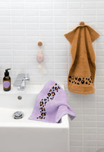 Leopard print cross-stitch bands on lavender and tan terry towels from Rico Design Acid Leo book