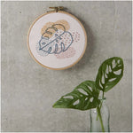 Rico Design Monstera Stickset im Holzring mit blauen, orangefarbenen und rosa Fäden