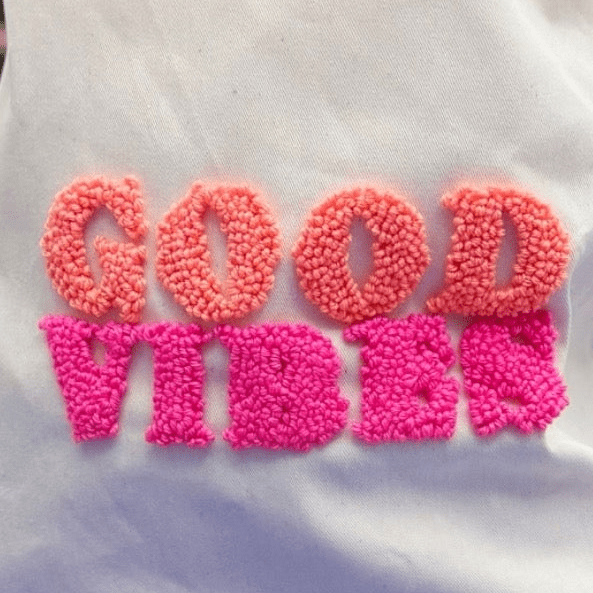 Good Vibes punch needle bag pattern detail showing peach and hot pink looped stitch texture on white fabric