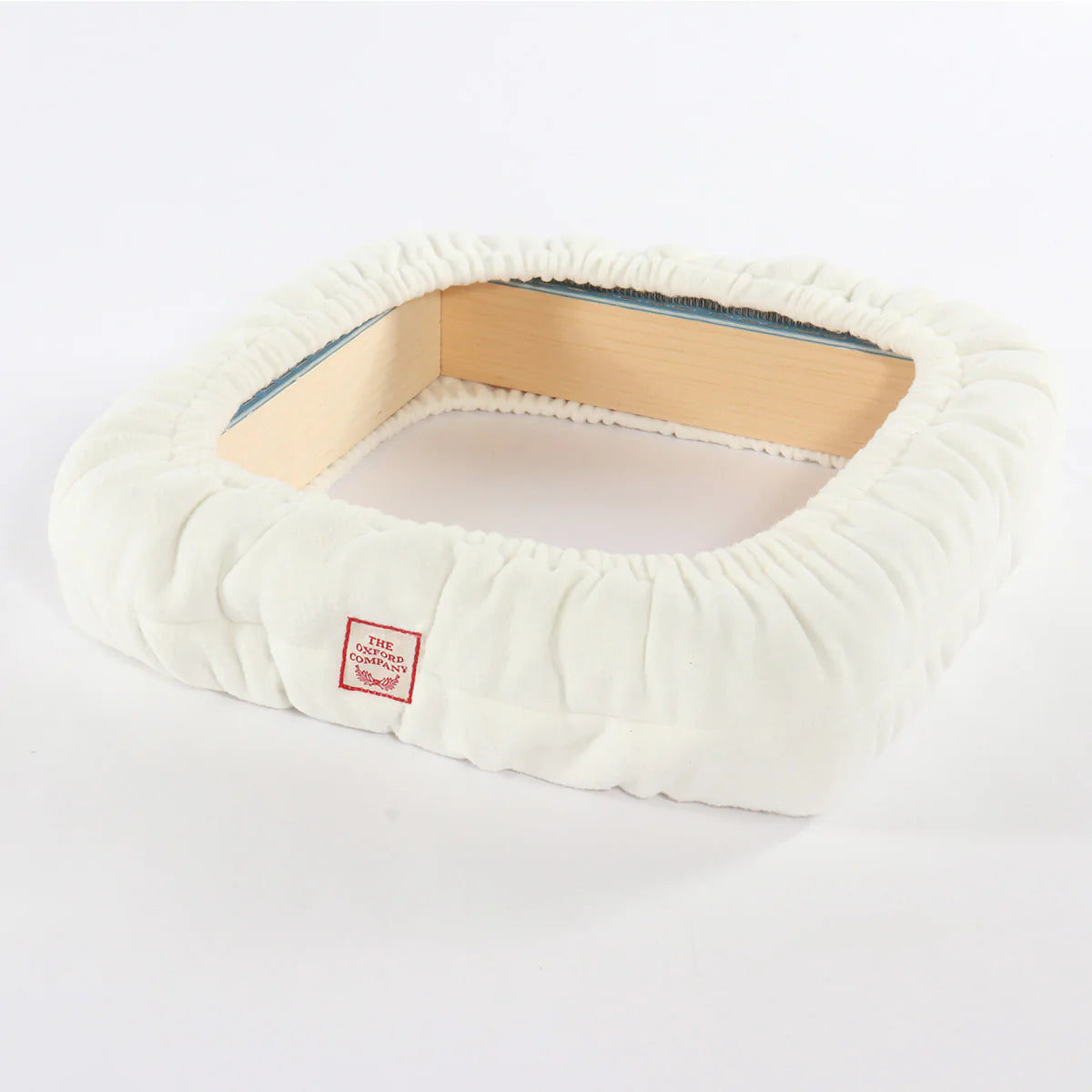 White padded frame cover protecting sharp gripper strips on wooden lap frame corner