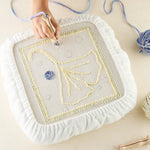 Hand using punch needle tool on white fleece covered frame for bird tufting pattern