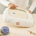 Punch needle project on cushioned Oxford frame cover with yellow blue yarn design
