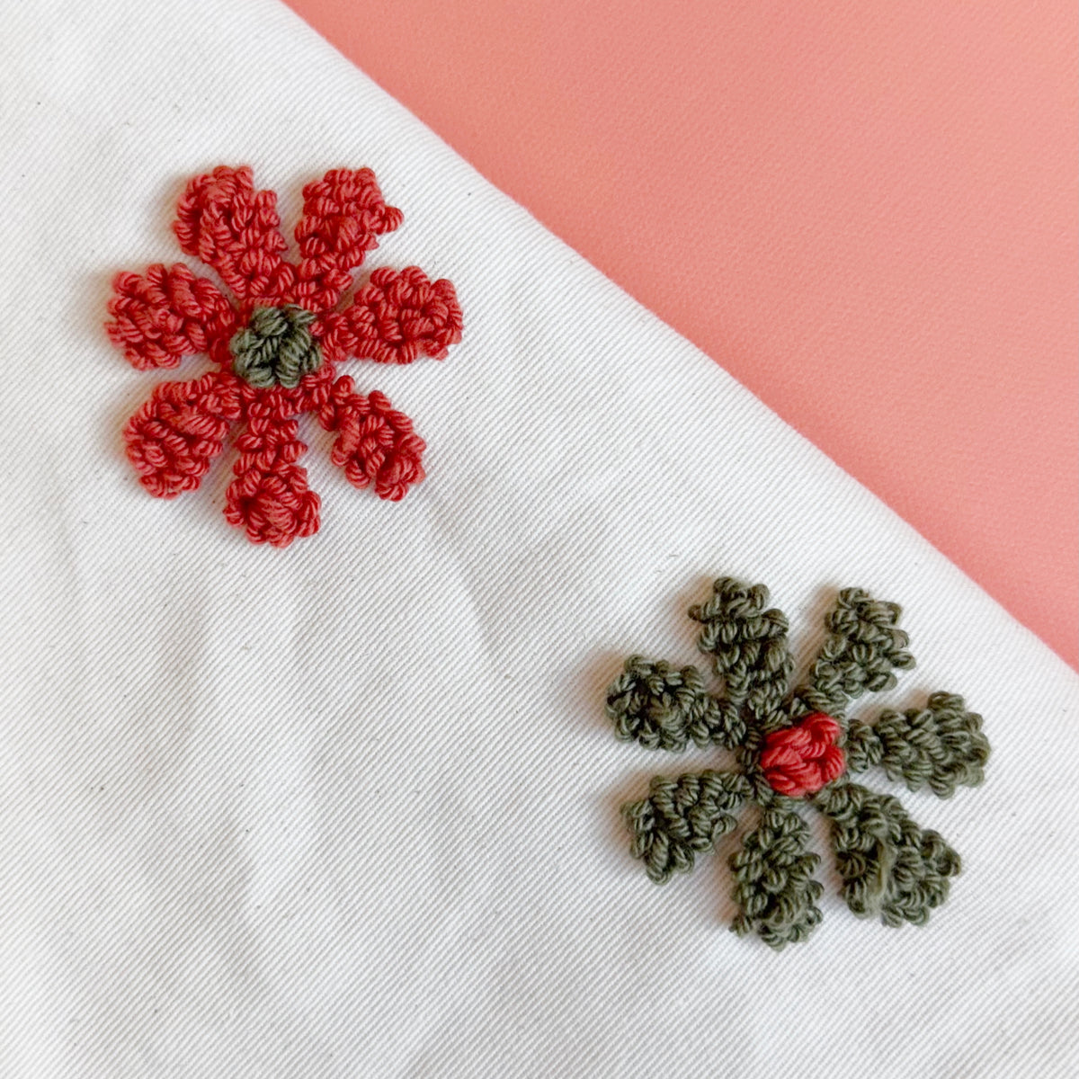 Close-up of textured loop stitches on tufted red and olive green yarn flowers